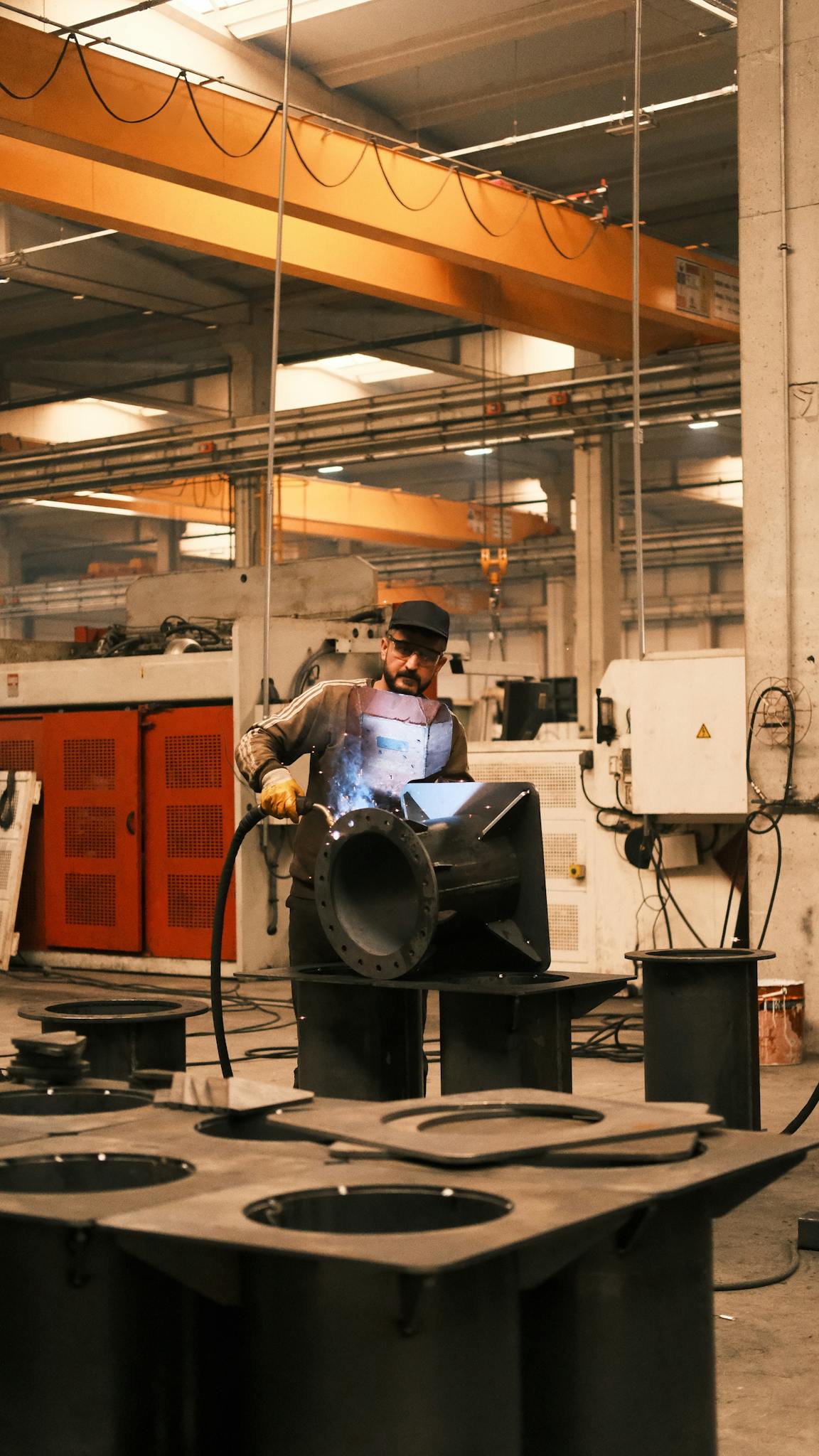 A craftsman welds metal parts in a busy industrial factory setting in Konya, Türkiye.